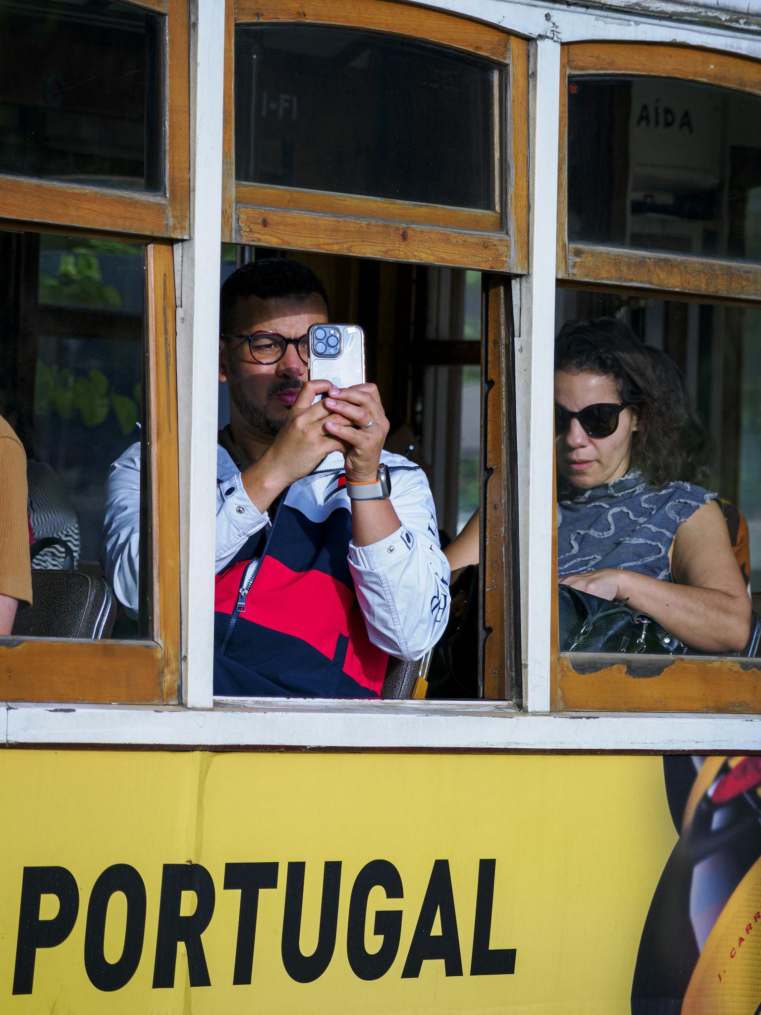 Tourists capturing moments on a tram ride in Portugal, highlighting travel and exploration.